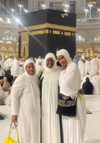 Trois pèlerines en blanc devant la Kaaba, à La Mecque